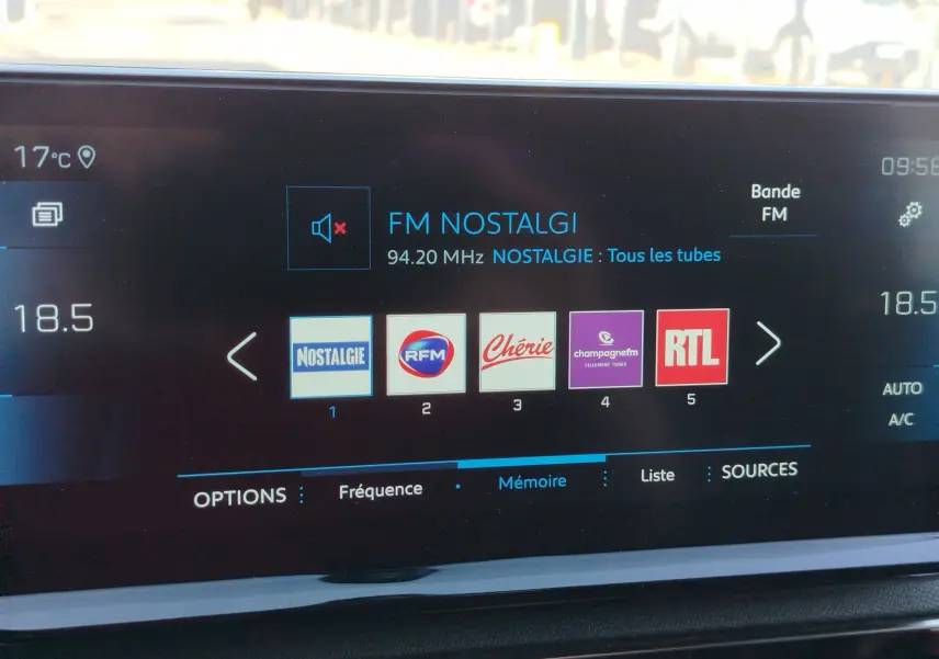 Écran tactile central du Peugeot 3008 2023 affichant les stations radio FM avec sélection sur Nostalgie, température à 18,5°C.