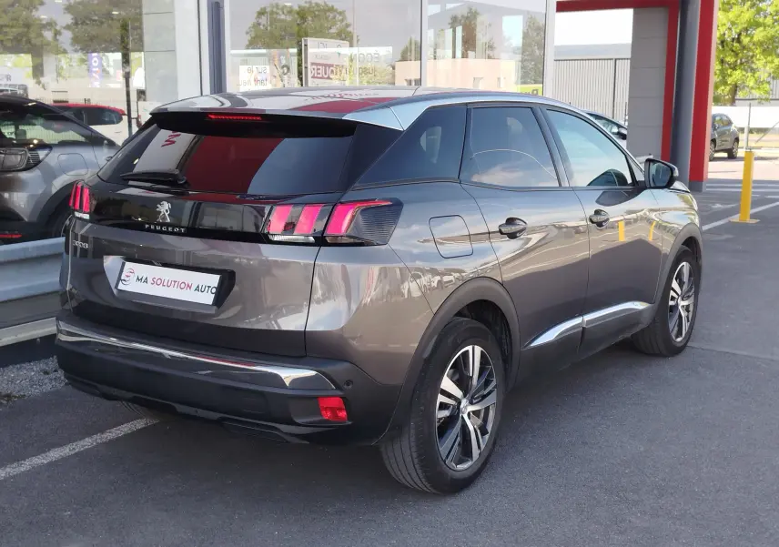 Vue 3/4 arrière droite d’un Peugeot 3008 gris Platinium 2023 avec feux arrière à griffes et jantes bi-ton.