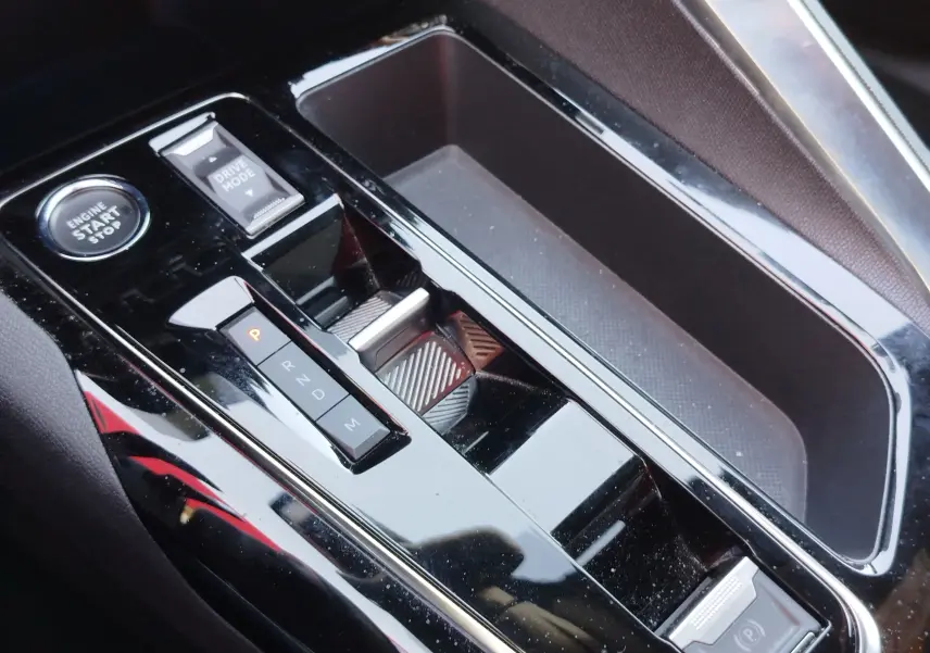 Gros plan sur la console centrale noire brillante du Peugeot 3008 2023 avec boutons de boîte auto et démarrage moteur.