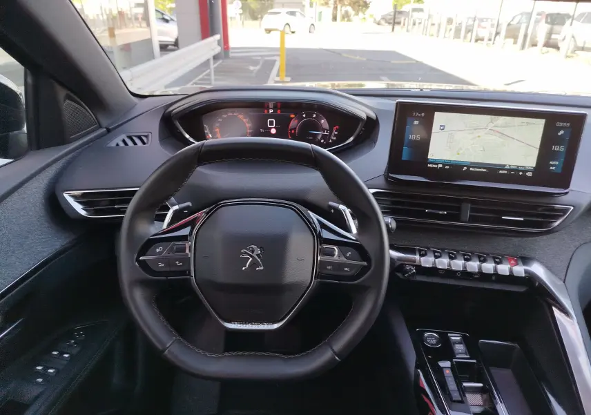 Vue intérieure centrée sur le volant compact et le tableau de bord numérique du Peugeot 3008 gris Platinium 2023.