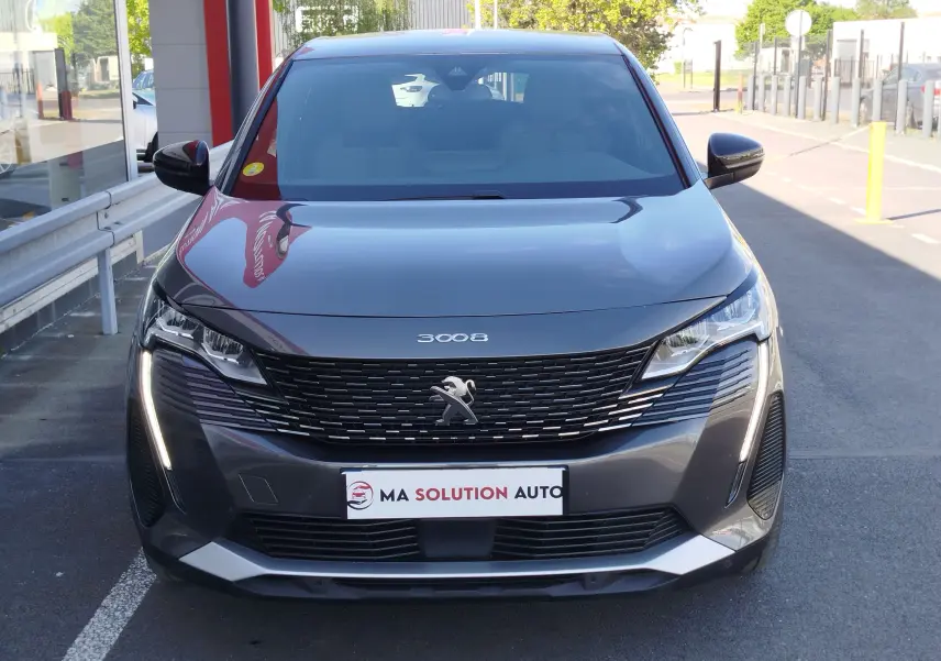 Vue frontale d'un Peugeot 3008 gris Platinium avec calandre noire et feux LED verticaux allumés.