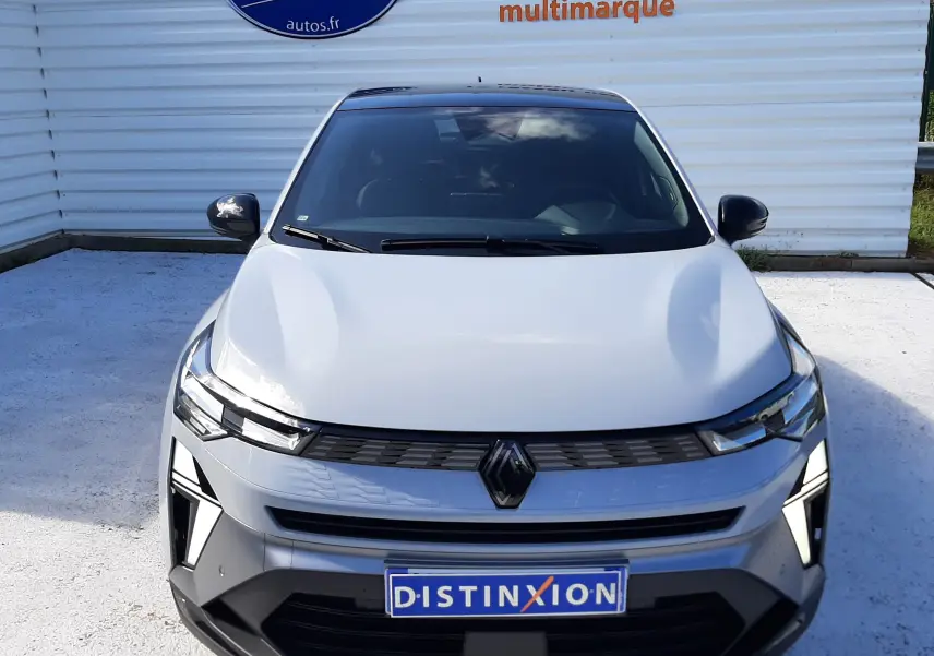 Vue avant d'une Renault Symbioz gris rafale avec calandre noire et phares LED, stationnée devant un mur blanc.