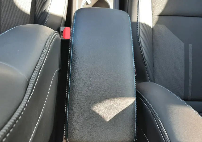 Vue plongeante sur l'accoudoir central en cuir noir avec surpiqûres blanches de la Renault Symbioz E-Tech Full Hybrid 2025.