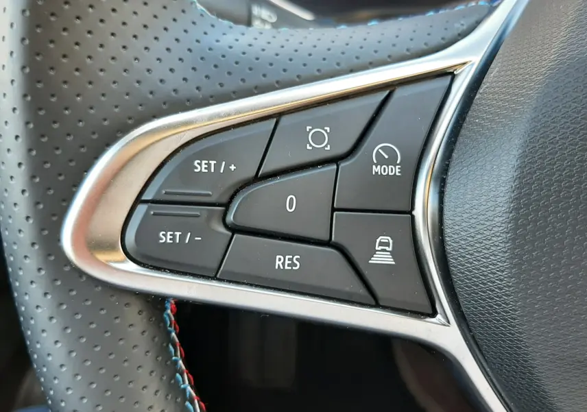 Gros plan sur les commandes de régulateur de vitesse au volant perforé gris du Renault Symbioz E-Tech Full Hybrid 2025.