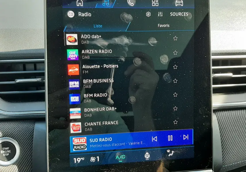 Écran tactile central du tableau de bord du Renault Symbioz gris Rafale, affichant la liste des radios DAB avec traces de doigts visibles.