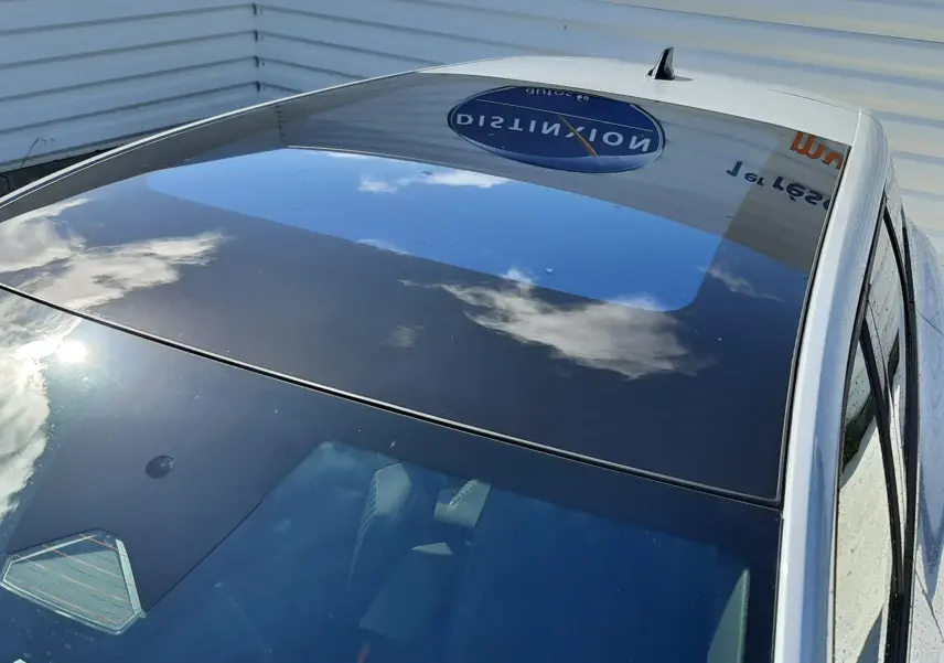 Toit panoramique en verre du Renault Symbioz gris Rafale, vu en plongée depuis l'avant droit, reflet du ciel visible.