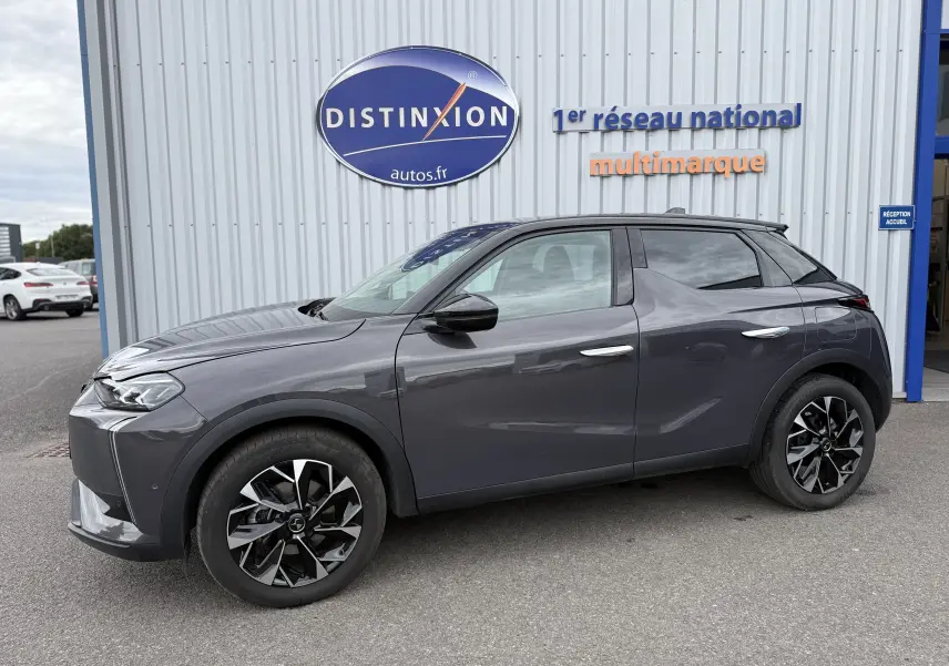 Vue de profil côté gauche d'une DS3 hybride 2025 gris foncé avec toit noir et jantes noires à motifs géométriques.
