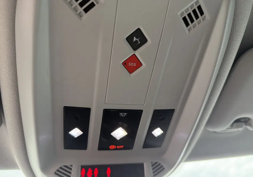 Vue en gros plan du plafonnier intérieur avec boutons SOS et éclairages LED allumés dans une DS3 hybride 2025.