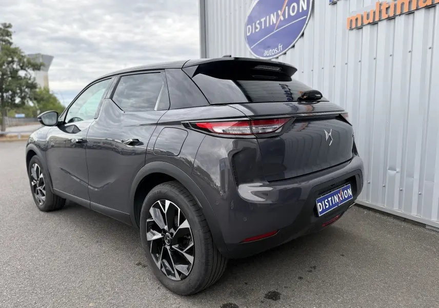 Vue 3/4 arrière droite d'une DS3 hybride 2025 gris Vol de Nuit avec toit noir Perla Nera et jantes bicolores.