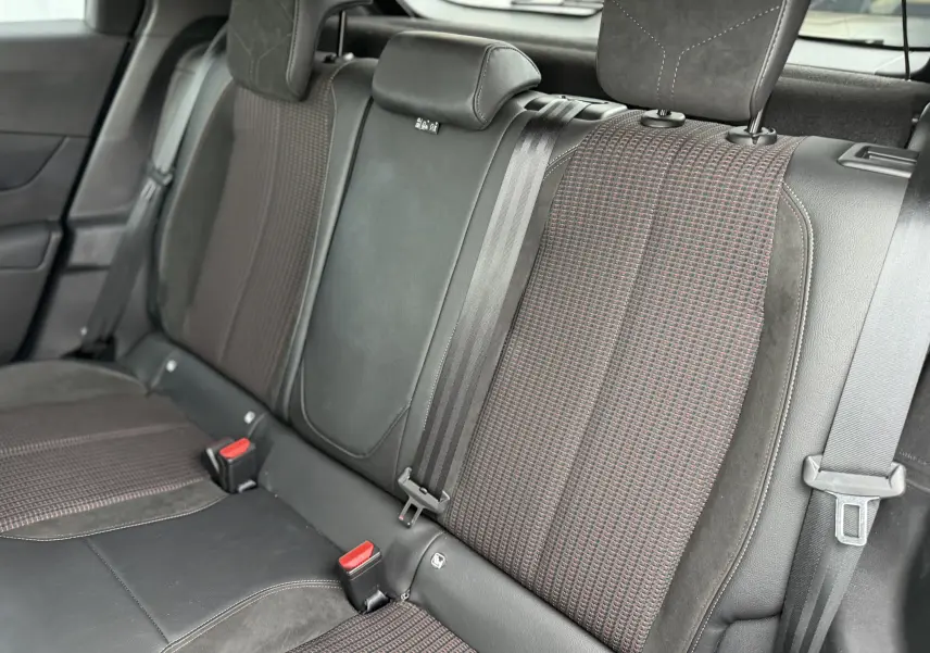 Vue rapprochée des sièges arrière du DS3 Hybride 2025, tissu à motif rouge et noir avec ceintures de sécurité visibles.