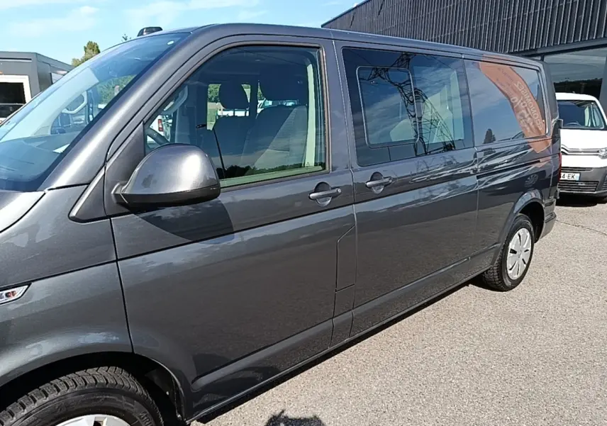 Vue de côté droit d’un Volkswagen Transporter gris foncé 2022, avec vitres latérales teintées et jantes acier.