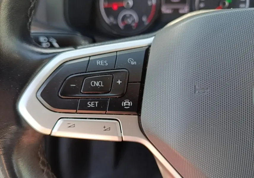 Gros plan sur le volant cuir multifonctions gris du Volkswagen Transporter 2.0 TDi 150 DSG7, avec commandes de régulateur.