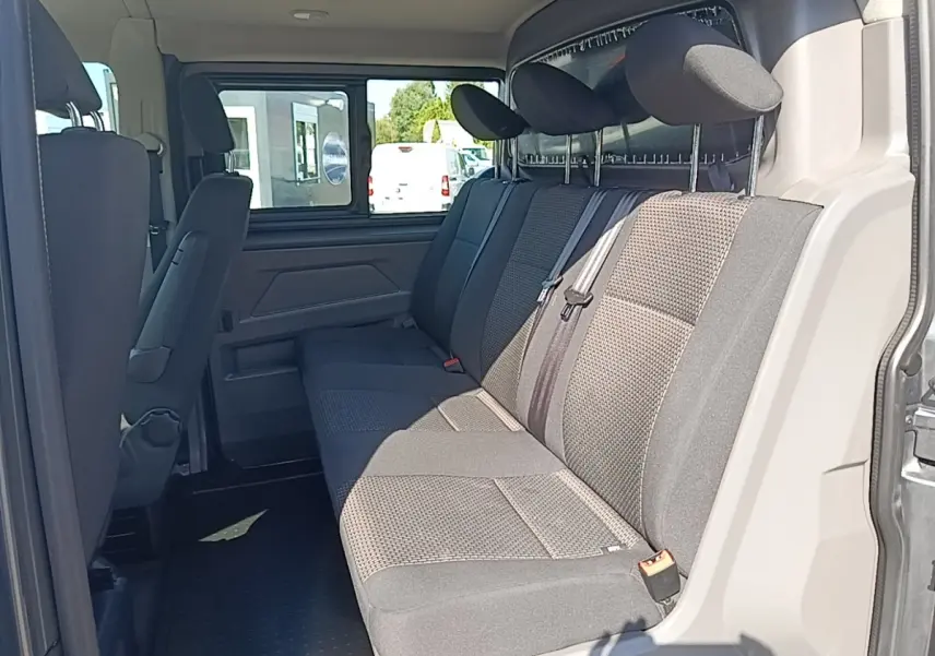 Vue intérieure côté droit sur la banquette arrière grise du Volkswagen Transporter 2022 avec appuie-têtes et ceinture de sécurité.