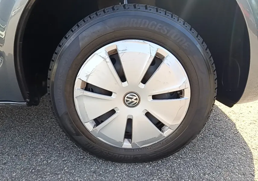 Gros plan sur la roue avant droite du Volkswagen Transporter gris foncé, jante acier avec enjoliveur VW marqué.