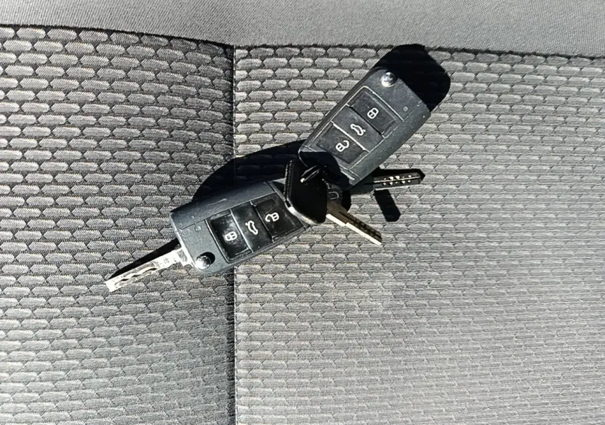 Gros plan sur deux clés Volkswagen noires posées sur un tissu gris texturé, sans vue du véhicule.