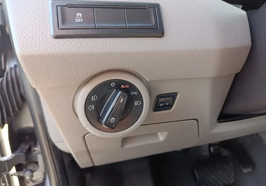 Gros plan sur le tableau de bord beige du Volkswagen Transporter 2022, avec commande des phares et pédale visible.