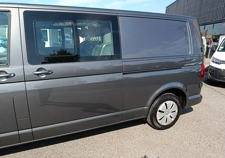 Vue latérale droite d'un Volkswagen Transporter 2.0 TDi gris foncé avec vitres arrière teintées et jantes acier.