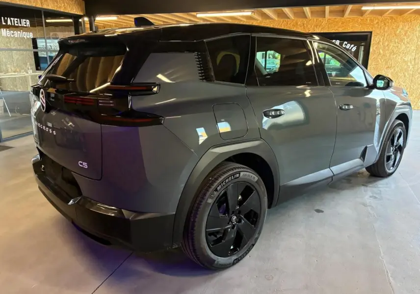 Vue 3/4 arrière droite du Citroën C5 Aircross 2026 vert avec jantes noires et toit noir en intérieur d'atelier.