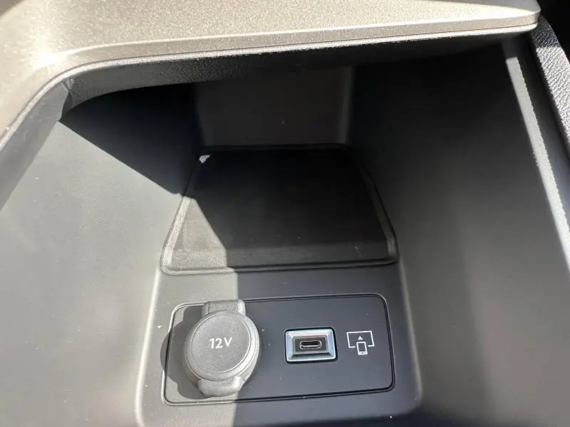 Vue rapprochée de la prise 12V et port USB-C dans le rangement central de la Peugeot 308 bleu 2025.
