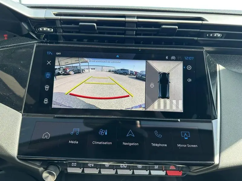 Écran tactile intérieur montrant la caméra de recul et la vue 360° d'une Peugeot 308 bleu, tableau de bord moderne.