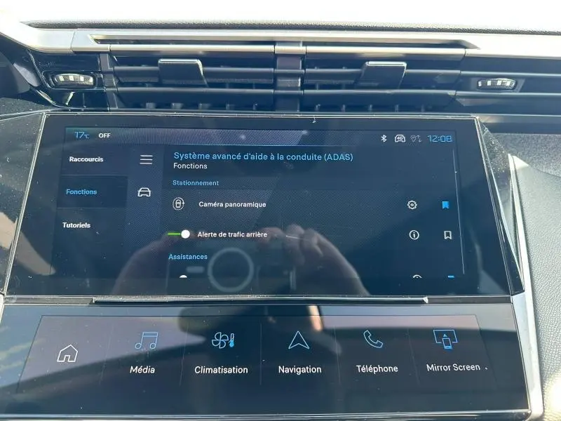 Vue rapprochée de l'écran tactile central du tableau de bord de la Peugeot 308 bleu, affichant les aides à la conduite.