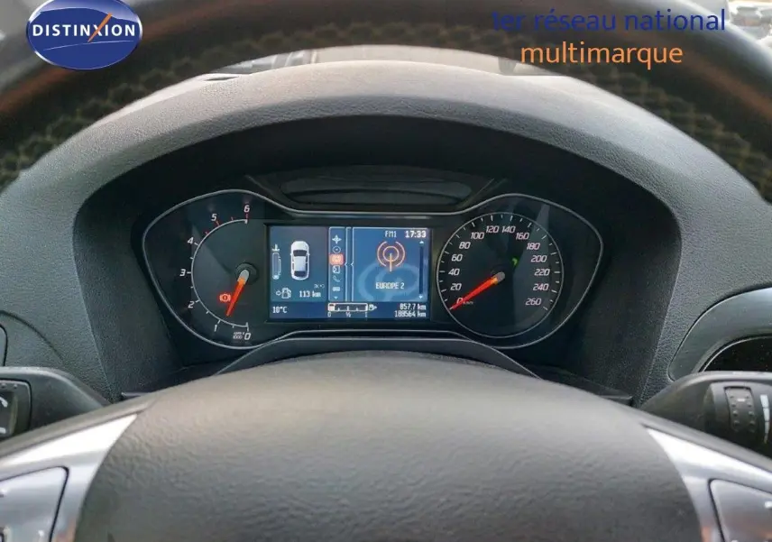 Tableau de bord et compteur numérique du Ford S-MAX gris clair, vue centrée depuis le volant.