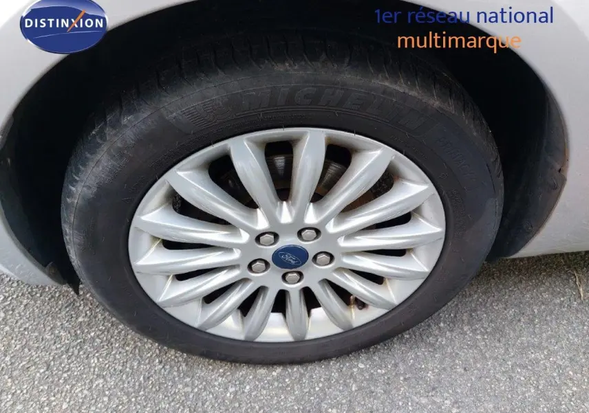Gros plan sur la roue avant droite gris clair métal d'une Ford S-MAX 2012 avec jante alliage multibranches.