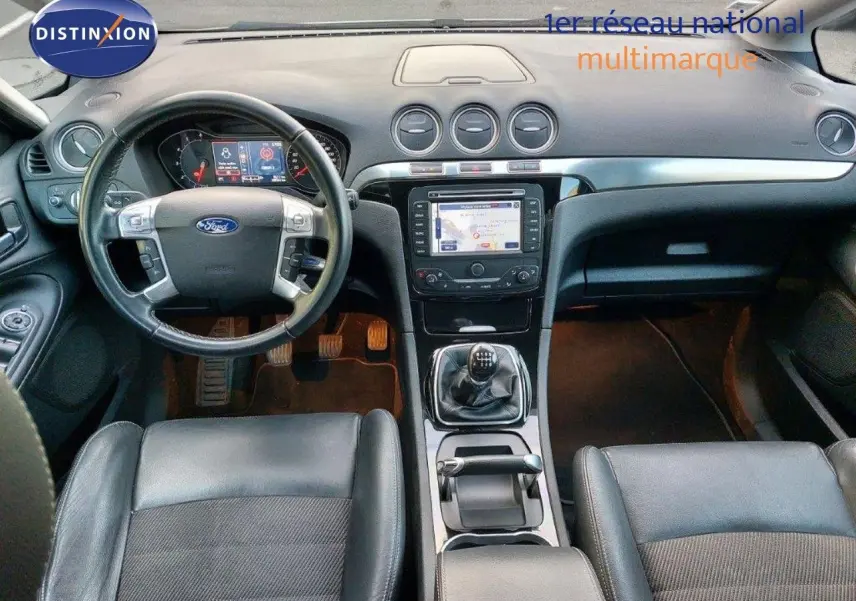 Vue intérieure du tableau de bord et console centrale du Ford S-MAX gris clair, avec volant multifonction et GPS intégré.