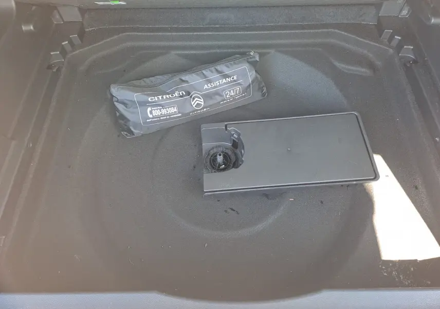 Coffre ouvert d'un Citroën C5 Aircross gris avec sac d'assistance et compartiment de rangement visible au centre.