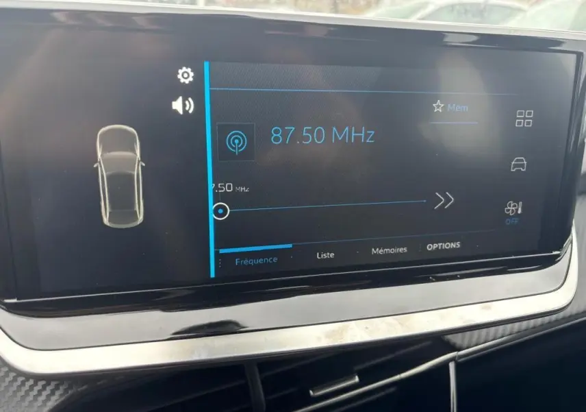 Écran tactile central affichant la radio à 87,50 MHz dans l’habitacle d’une Peugeot 208 gris 2025.