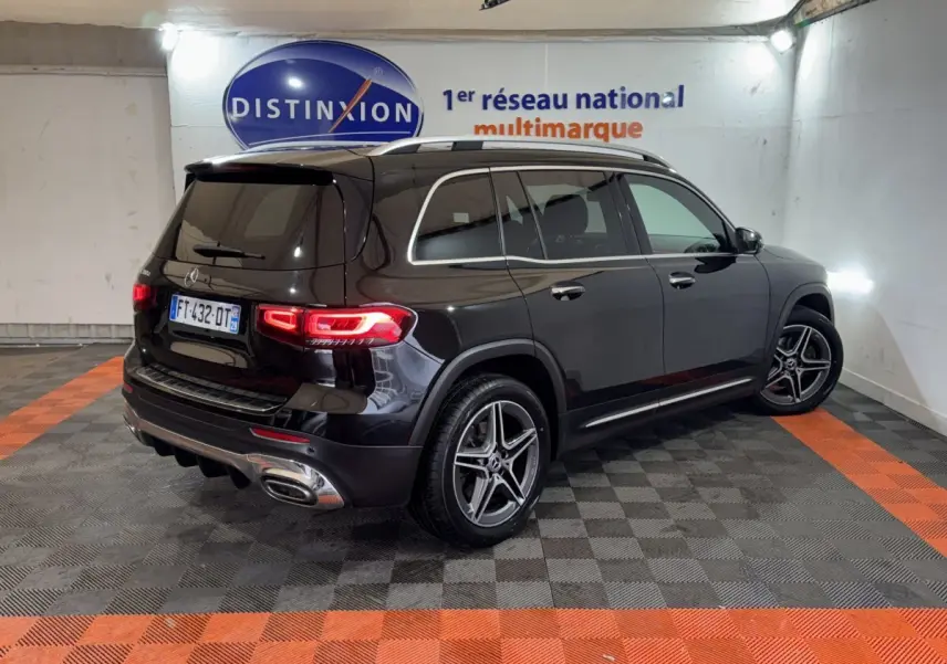 Vue 3/4 arrière droite d’un Mercedes GLB 200 d AMG Line noir, avec jantes AMG et feux arrière LED allumés.