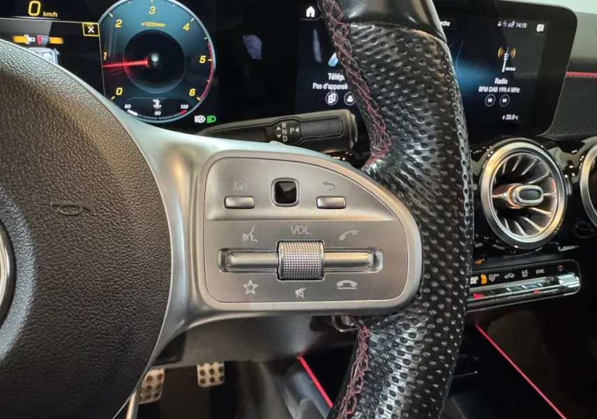 Gros plan sur le volant en cuir noir perforé avec commandes intégrées et tableau de bord numérique du Mercedes GLB 200 d AMG Line.
