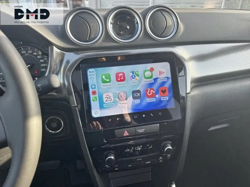 Vue intérieure centrée sur la console centrale noire du Suzuki Vitara avec écran tactile et aérateurs ronds au-dessus.