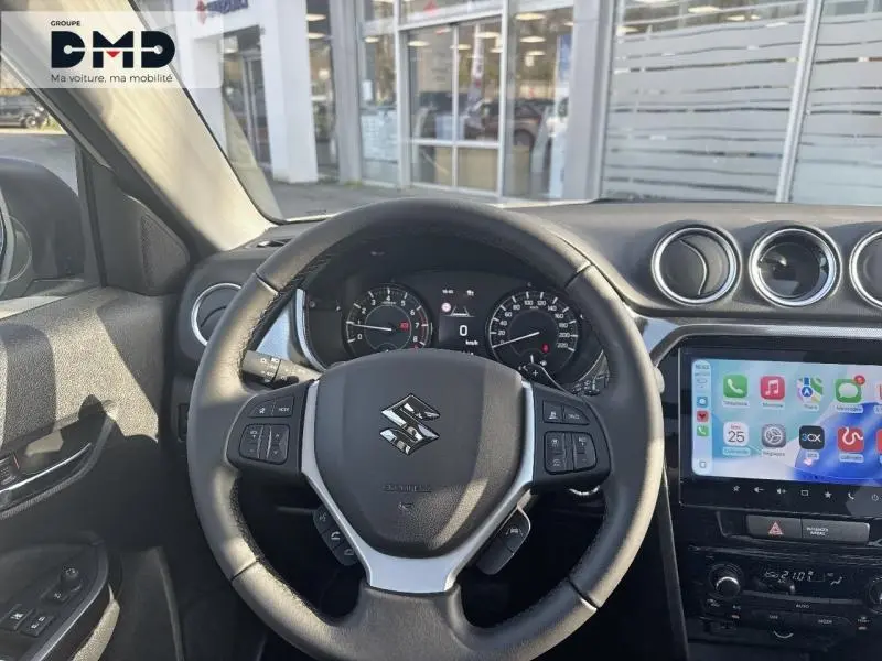 Vue intérieure centrée sur le volant cuir multifonction du Suzuki Vitara 1.4 hybride avec écran tactile et tableau de bord visible.