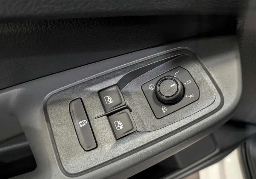 Gros plan sur les commandes de réglage des rétroviseurs et des vitres côté conducteur du Volkswagen Caddy blanc 2025.