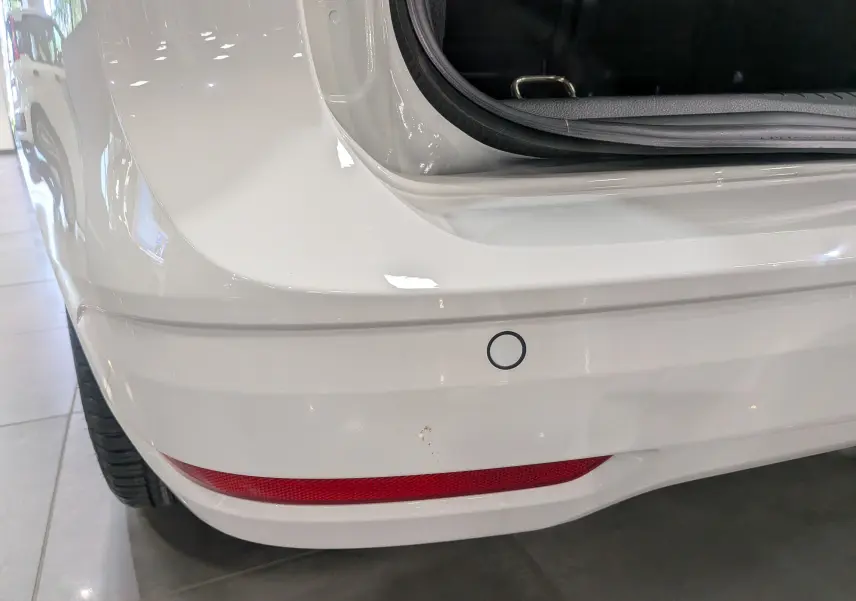 Gros plan sur le pare-chocs arrière blanc du Volkswagen Caddy 2.0 TDI avec capteur de recul et feu rouge intégré.