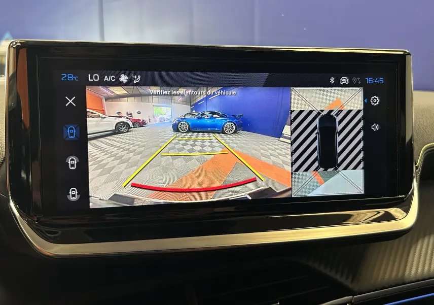 Écran tactile montrant la caméra de recul avec vue arrière d’un véhicule bleu dans un garage intérieur.