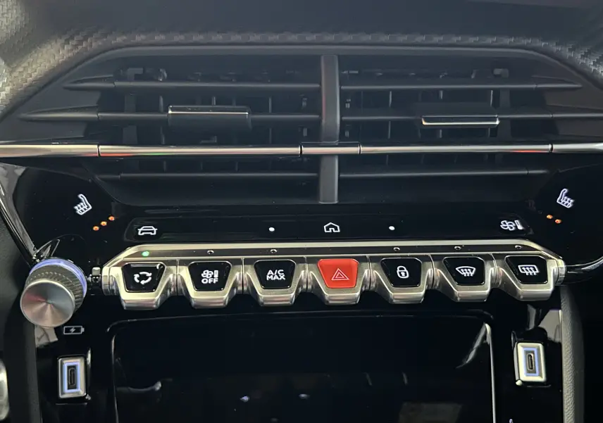 Vue rapprochée de la console centrale noire du Peugeot 2008 Hybrid 2025, avec boutons chromés et commandes tactiles.