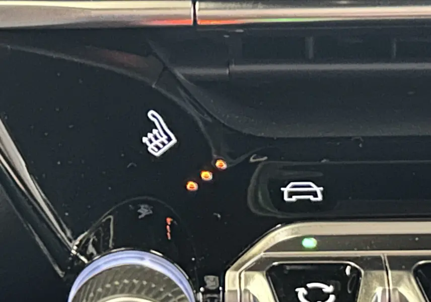 Détail du tableau de bord noir du Peugeot 2008 Hybrid, montrant le bouton de siège chauffant avec trois voyants allumés.