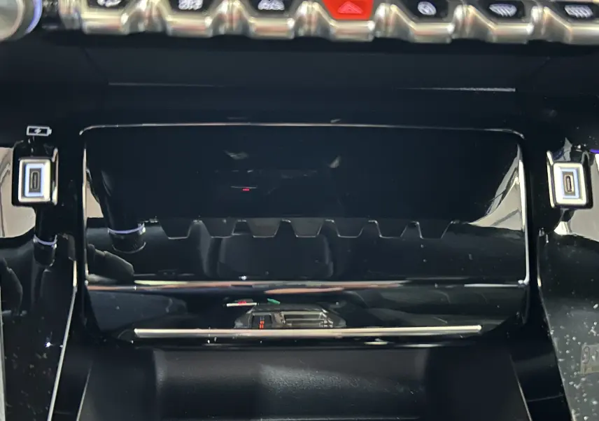 Gros plan sur la console centrale noire brillante du Peugeot 2008 Hybrid 136 e-DCS6 GT avec boutons et ports USB visibles.