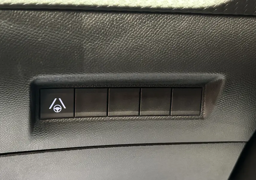 Bouton de commande d'aide au maintien de voie sur tableau de bord noir d'un Peugeot 2008 Hybrid 2025.