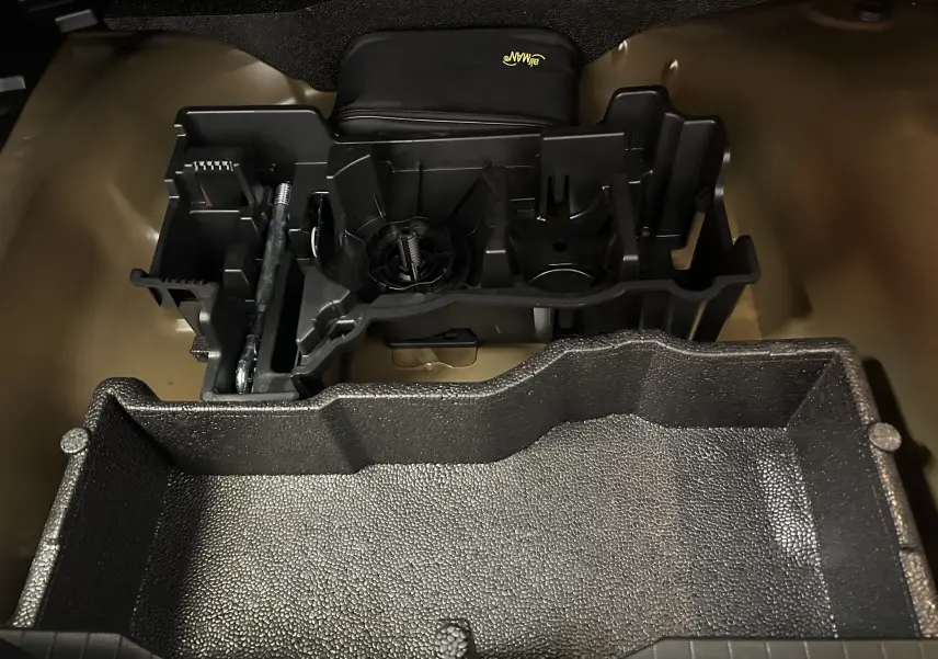 Coffre ouvert en vue plongeante montrant le rangement modulable et les accessoires noirs du Peugeot 2008 Hybrid 136 e-DCS6 GT.