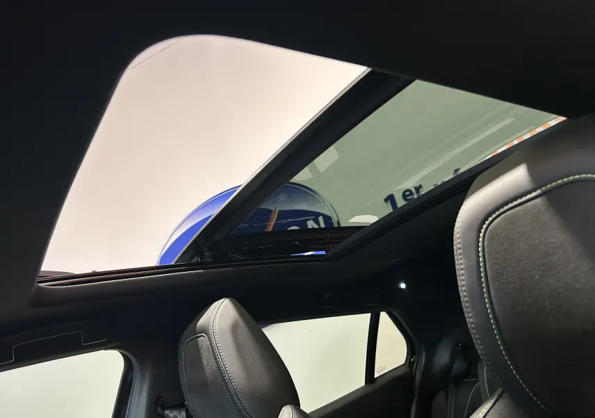 Vue intérieure du toit ouvrant panoramique et des sièges avant en cuir noir du Peugeot 2008 Hybrid 136 e-DCS6 GT noir.