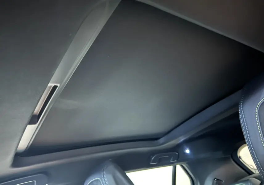 Vue intérieure du toit ouvrant panoramique fermé du Peugeot 2008 Hybrid 136 e-DCS6 GT noir, avec partie du siège avant visible.