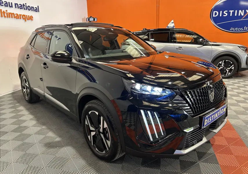 Peugeot 2008 Hybrid 136 e-DCS6 GT noir en 3/4 avant droit avec phares allumés et calandre distinctive.