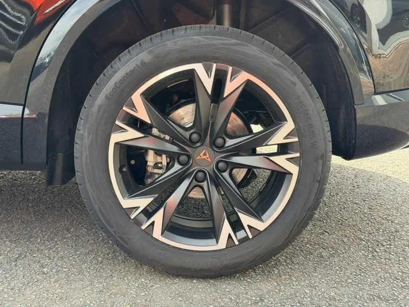 Gros plan sur la roue avant droite du CUPRA Formentor bleu, avec jante alu noire et argent au design anguleux.