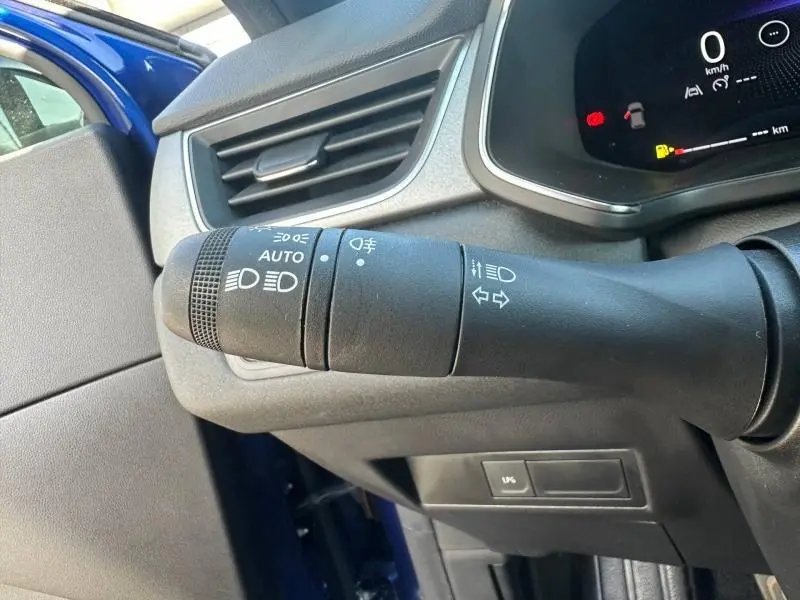 Gros plan sur la manette des feux du Renault Captur 2025 Bleu Iron, avec tableau de bord et porte côté gauche visibles.