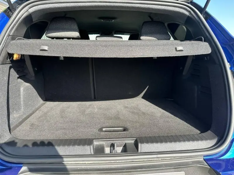 Coffre ouvert vu de l'arrière d'un Renault Captur 2025 Bleu Iron/Noir Etoilé, montrant l'espace de chargement vide.