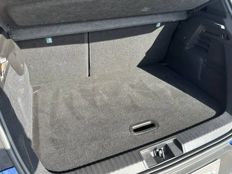 Vue intérieure du coffre spacieux et propre du Renault Captur 2025, avec tapis noir et ouverture de poignée visible.