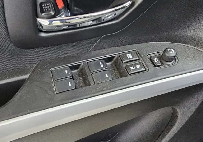 Gros plan sur la commande des vitres électriques et réglage des rétroviseurs côté conducteur d'une Suzuki SX4 S-Cross 2020 noire.